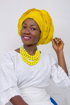 an African lady with head tie, bead necklace, beautiful makeup and smiling