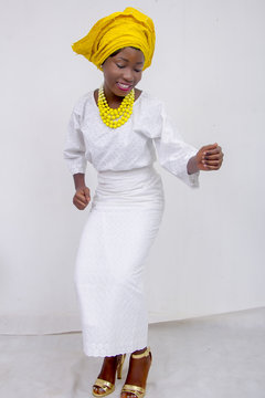 an African lady with head tie, bead necklace, beautiful makeup and smiling and dancing