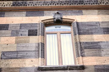 Carved stone pattern on the cornice and arched window frame with the stylized sheet ornament in the center
