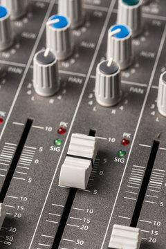 Audio mixing console with sliders and knobs on the channels.