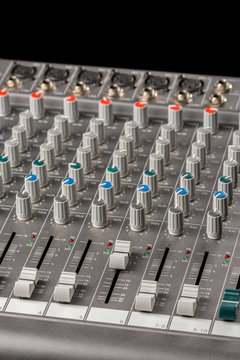 Audio mixing console with sliders and knobs on the channels.
