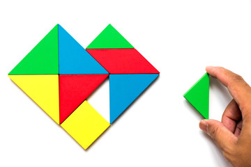 Colorful wooden tangram puzzle in heart shape wait to fulfill with triangle shape on white background