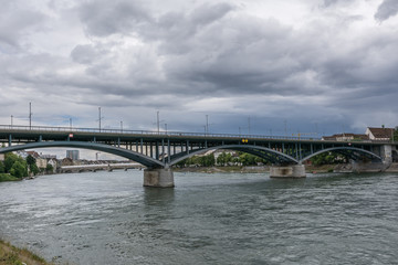Fototapeta na wymiar Basel am Rhein mit Brücke und wolkigem Himmel