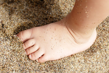 Child's feet in the sand close-up