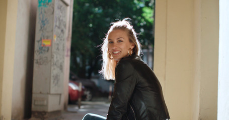 Pretty fashion woman sitting on stairs. Happy stylish girl enjoying summer in a city in Europe.