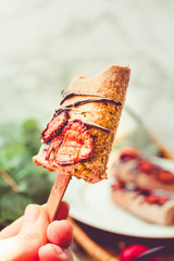 Hand holding a cocoa ice cream popsicles with chocolate and strawberries. Toned Effect. Space for text.