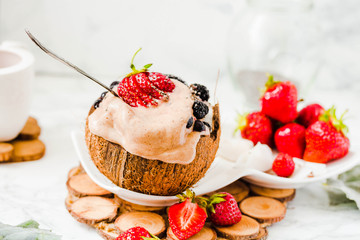 Ice cream with peanut butter, buckwheat and strawberries on coconut cup.Marble background.Vegan or diet food concept.