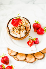 Ice cream with peanut butter, buckwheat and strawberries on coconut cup.Marble background.Vegan or diet food concept.