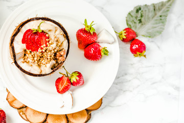 Ice cream with peanut butter, buckwheat and strawberries on coconut cup.Marble background.Top view.