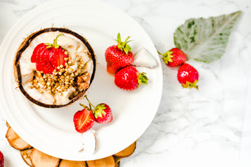 Ice cream with peanut butter, buckwheat and strawberries on coconut cup.Marble background.Vegan or diet food concept.