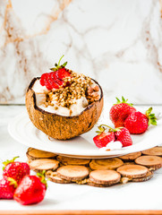 Ice cream with peanut butter, buckwheat and strawberries on coconut cup.Marble background.Selective focus