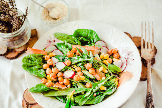 Green salad with arugula, corn, carrots and baked chickpeas.Healthy vegetarian meal concept.
