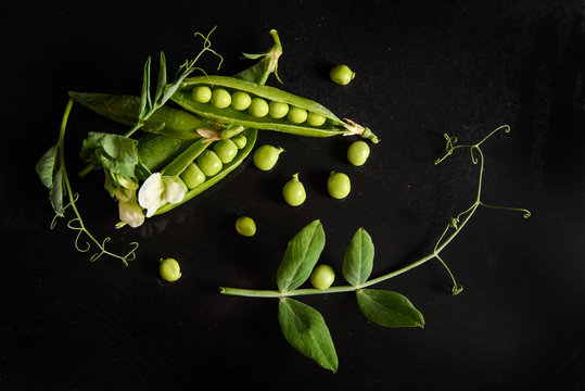 green pea pod, green peas, black background, flat lay, top view 