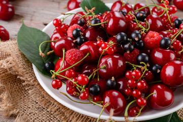 Mature cherries on a plate on a wooden table
