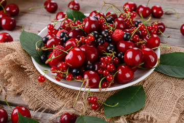 Mature cherries on a plate on a wooden table