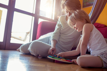Happy mother and girl daughter playing on living room wooden floor.Happy relaxed parents enjoying life with their children.Family at home. Bright sunny light