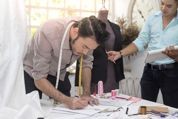 Young team asian designer warking at studio. Fashion designer carefully creating new fashionable styles. Dressmaker makes clothes via additional part-time job.