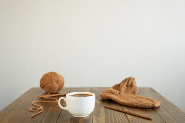Coffee, woolen sock and knitting on a table