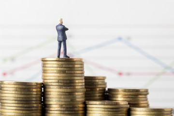 Miniature model of businessman thinking with project for investment standing coin.