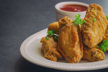 Fried chicken wings on white plate served with barbecue dipping sauce. Homemade fried chicken delicious and crispy. Close up fried chicken and chili sauce or tomato sauce (ketchup) ready to served