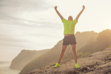 Success of a man after jogging / exercising on a clif near the sea / ocean.