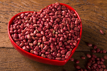 Raw peanuts in heart bowl.