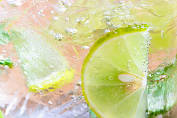 Close up concept on piece of lemon or lime in lemonade for wallpaper or background. Half-circle of lemon or lime in sparkling water (soda) in natural tone. Water bubble and half-circle lemon or lime.