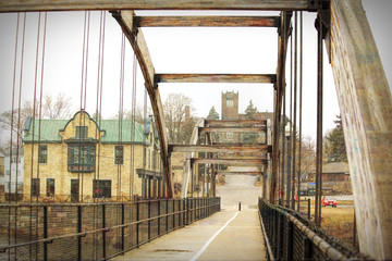 An arched walk bridge leades to a building with a clocktower.
