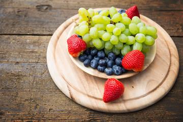 Fresh grapes, blueberries and Strawberries in a bowl on wooden table