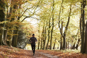 Mature Man Running Through Autumn Woodland
