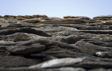 Background: typical roof of stone slabs (with mosses and lichens) of an old high mountain hut. The slab is called "losa" (pioda or beola), generally used in roofing or flooring, alps, switzerland