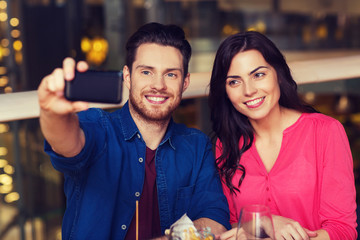 couple taking selfie by smartphone at restaurant