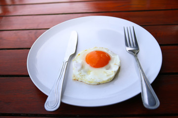 Healthy breakfast with fried egg on wooden table.