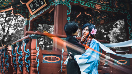 Two couples hugging near a Japanese pergola. Format 16:9 (film frame).