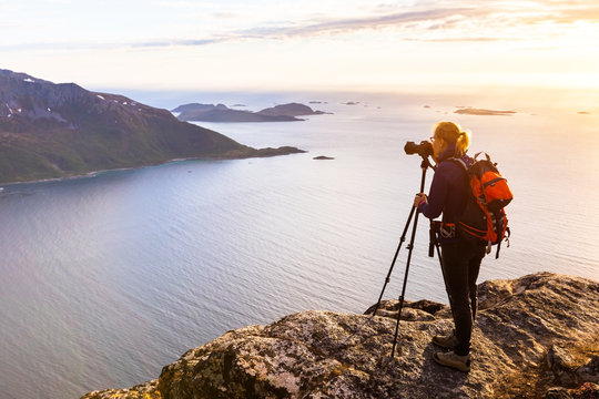 Woman photographer photographing fjord in Norway with DSLR and tripod