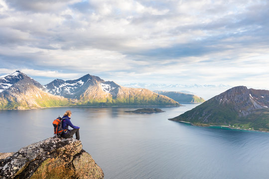Woman hiker looking at a beautiful Norwegian Fjord landscape © NicoElNino