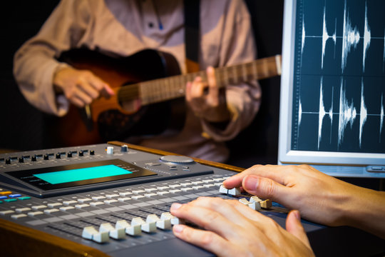 sound engineer hands working on digital sound mixer for acoustic guitar recording in music studio