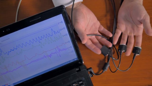Man's hands connected to the lie detector circuit.
