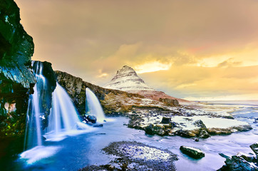 View of the Kirkjufell Mountain with Kirkjufellsfoss Waterfall at dusk in Iceland.