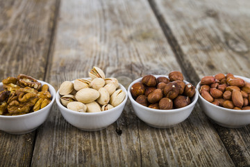 Four bowls with nuts on a  wooden table