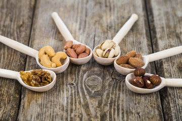 Nuts in a wooden spoons on a  wooden table.
