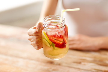 close up of woman holding glass with fruit water