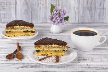 Chocolate piece of cake from biscuit dough with poppy seed, prune and walnuts and cup of coffee