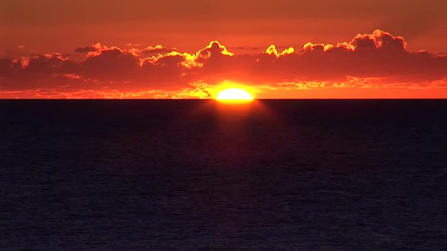 Breathtaking sunset with fiery clouds in a tropical island, with natural stereo sounds  View of a glorious sun setting until it disappears completely beyond the horizon