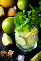 Mojito cocktail in  glass with lime, fresh mint and ice on a dark background. Selective focus.