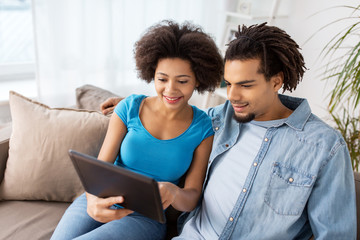 smiling happy couple with tablet pc at home