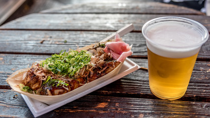 Okonomiyaki street food and a glass of beer in Osaka, Japan