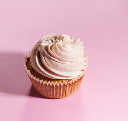 Closeup of tasty cupcakes with cream. Pink Background.