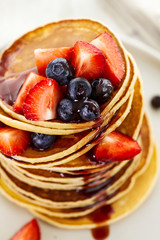 Beautiful Tasty Appetizing Stack Pile of Pancakes with Fresh Summer Fruits and Syrup. Closeup. Bright Background.