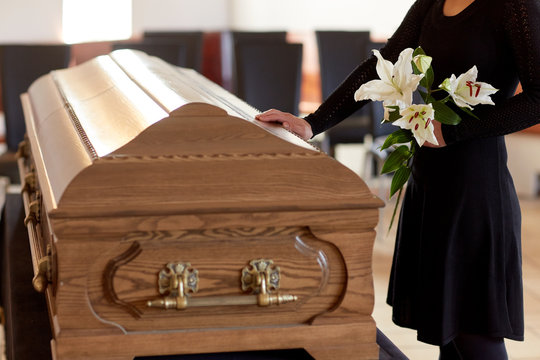 Woman With Lily Flowers And Coffin At Funeral